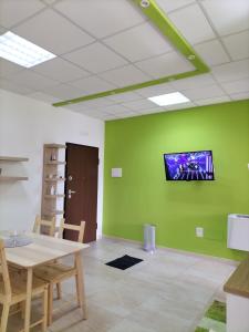 Habitación con mesa y TV en una pared verde. en TWIN HOUSE en Tito