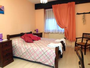 Un dormitorio con una cama con almohadas rojas y una ventana en B&B Gli Eremiti, en Andorno Micca