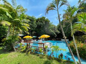 una piscina del complejo con mesas, sombrillas y palmeras en Beloalter Hotel, en Alter do Chao