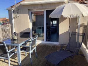een tafel en stoelen met een parasol op een terras bij Chaleureux T2 30 m2 et sa terrasse bois 18 m2 in La Rochelle