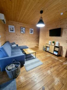 a living room with a blue couch and a tv at Fuledzki Biały Domek - Mazury, Jacuzzi, Sauna, Giżycko in Fuleda