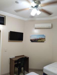 a living room with a ceiling fan and a desk at Villa Jeshua Simmonds in Guayaquil