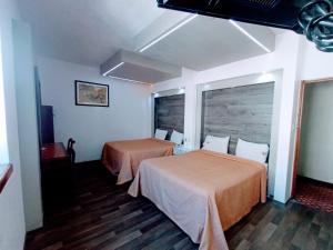 een hotelkamer met 2 bedden en een raam bij Hotel Mina in Mexico-Stad