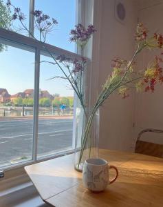 un jarrón de flores sentado en una mesa junto a una ventana en Bristol townhouse with harbour views. Sleeps 7, en Bristol