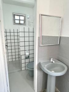 a bathroom with a sink and a toilet and a mirror at Pousada Kawaii in Arraial d'Ajuda