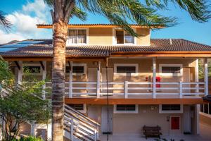 a house with a balcony and a palm tree at Ciribaí Praia Hotel in Pauba