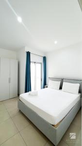 a bedroom with a large white bed with blue curtains at Ka Djula in Sal Rei