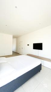a white bedroom with a large bed and a flat screen tv at Ka Djula in Sal Rei