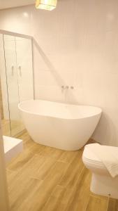 a white bathroom with a tub and a toilet at Baía Branca Beach Resort in Tamandaré