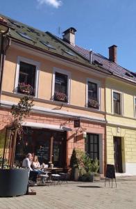 dos personas sentadas en mesas fuera de un edificio en Historický apartmán v centre mesta-2min pešo na námestie, en Banská Bystrica