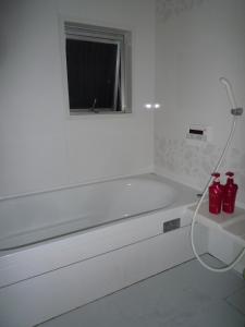 a white bathroom with a bath tub with a window at Osaka Kuma House in Osaka +43 photos