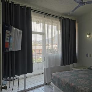 a bedroom with black curtains and a large window at 1 BR APT with AC , TV , wi-fi near DT and beach in Zihuatanejo