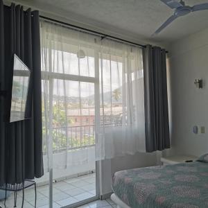 a bedroom with a large window with a view at 1 BR APT with AC , TV , wi-fi near DT and beach in Zihuatanejo