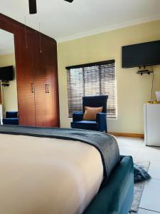 a bedroom with a bed and two chairs and a window at Bloom Guest House in Pretoria