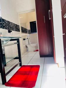 a bathroom with a red rug next to a toilet at Bloom Guest House in Pretoria