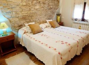 - une chambre avec un grand lit et un mur en pierre dans l'établissement Casa rural marga, à Tardienta