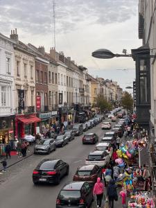 uma movimentada rua da cidade com carros estacionados na berma da estrada em Duplex situé a 2min de la gare du nord em Bruxelas