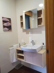 Baño blanco con lavabo y espejo en CASA NOGUEIRA, en Allariz