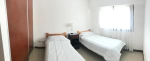 2 camas en una habitación pequeña con ventana en Departamento de categoría en macrocentro Echeverria en Río Cuarto