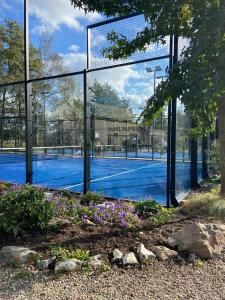 a tennis court with a fence and flowers at Casa Nymphaea in Kinrooi