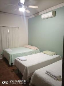 a room with two beds and a ceiling fan at Casa del Campo in Tela