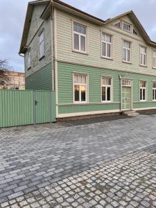 a green house on a cobblestone street at Posti Guest Apartment in Haapsalu