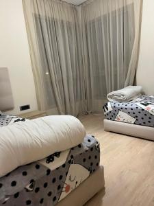 - 2 lits dans une chambre avec des draps noirs et blancs dans l'établissement Prestigia golf piscine appartement lux opale 3 chambre, à Marrakech