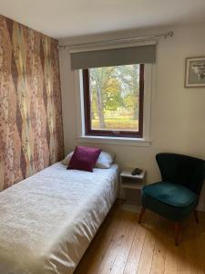 1 dormitorio con cama, ventana y silla en Flanders Fields, en Dingwall