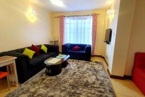 soggiorno con divano nero e cuscini gialli e rossi di Spacious 2bedroom condo w free parking on premises a Nairobi
