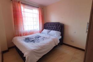 a bedroom with a large bed with a window at Spacious 2bedroom condo w free parking on premises in Nairobi