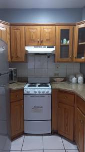 Il comprend une cuisine équipée d'une cuisinière blanche et de placards en bois. dans l'établissement Beach One Bedroom 2, à Ocho Rios