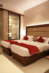 - une chambre avec un grand lit et des oreillers rouges dans l'établissement Hotel Gurudev Grand, à Kalyan
