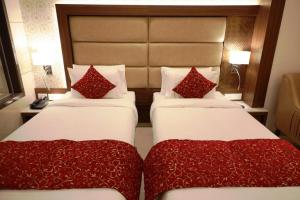 - 2 lits avec des oreillers rouges dans une chambre d'hôtel dans l'établissement Hotel Gurudev Grand, à Kalyan
