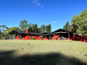 una casa roja con techo negro en un campo en El Lucero, estancia, en Mar de Ajó