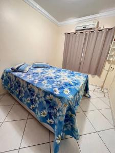 1 dormitorio con 1 cama con una manta de flores azules en Casa Aconchegante no Centro de Foz do Iguaçu, en Foz do Iguaçu