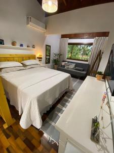1 dormitorio con 1 cama blanca grande y 1 sofá en Refugio Na Praia Hospedagem - Guarda Do Embaú en Guarda do Embaú