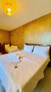 a bedroom with a large white bed with a laptop on it at Pousada Casa Do Alemão in Flecheiras