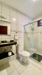 a bathroom with a toilet and a glass shower at Pousada Casa Do Alemão in Flecheiras