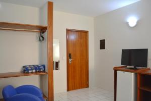 a room with a door and a tv and blue chairs at Sara Palace Hotel in Uberlândia