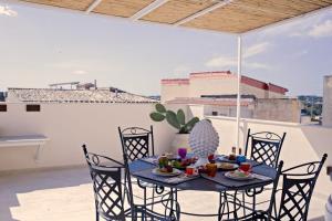 einen Tisch mit Stühlen und Essen auf einem Balkon in der Unterkunft La Dimora sotto le Stelle in Noto