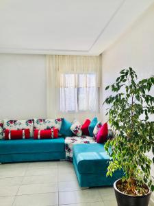 un sofá azul en una sala de estar con una planta en Marbella Beach location pour famille 2 chambres en Minaret de Mansuria