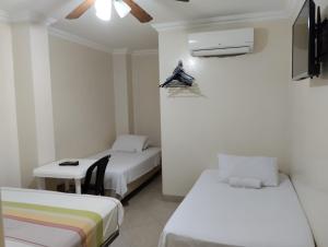 a room with two beds and a table and a tv at Jeshua Simmonds Inn in Guayaquil