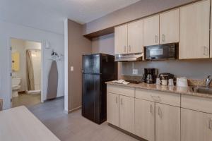 a kitchen with a black refrigerator and wooden cabinets at Studio 6-El Paso, TX - East in Loma Terrace