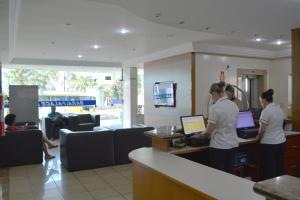 a group of people standing at a counter in a lobby at Sara Palace Hotel in Uberlândia