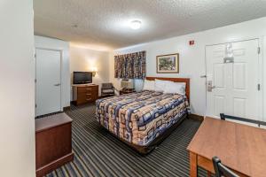 a hotel room with a bed and a table at Studio 6 Greensboro NC I40 in Greensboro