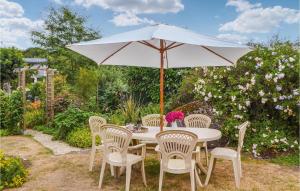 a white table with chairs and an umbrella at Gorgeous Home In Trégunc With Kitchen in Kerguillaouet +36 photos