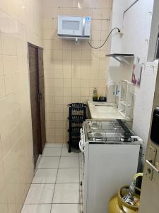 a small kitchen with a stove and a microwave at Kit do ALEX - AVIAÇÃO - a uma esquina da praia - Ar Condicionado in Praia Grande +6 photos