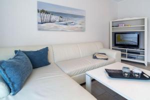 salon z białą kanapą i telewizorem w obiekcie Ferienwohnung-Leuchtfeuer-1-EG w mieście Norddeich