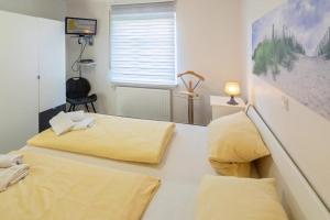 sypialnia z 2 łóżkami z żółtą pościelą i oknem w obiekcie Ferienwohnung-Leuchtfeuer-1-EG w mieście Norddeich