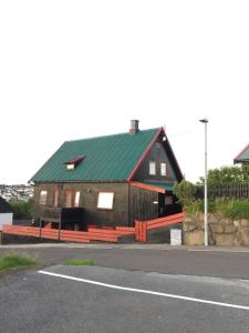 ein großes Holzhaus mit grünem Dach auf einer Straße in der Unterkunft Apartment in the center of Tórshavn, free parking. in Tórshavn